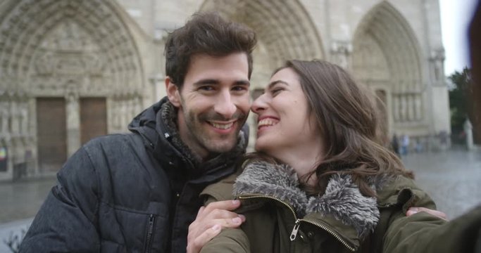 Tourist couple taking selfie photograph in front of Notre Dame Paris smartphone in city sharing lifestyle photo enjoying  holiday European   vacation travel adventure 