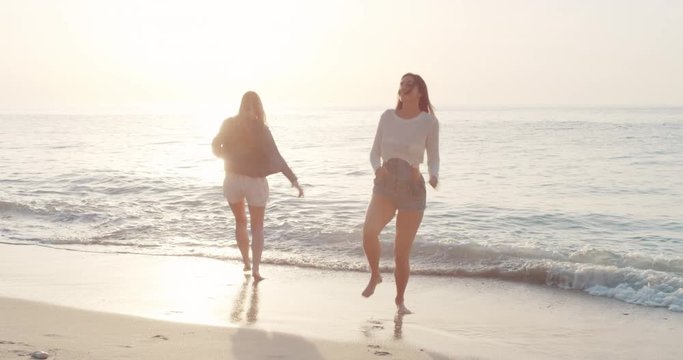 Teenager Girl friends dancing on tropical beach island freestyle dance outdoors celebrating summer travel adventure wearing hipster denim shorts