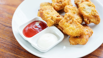 chicken nuggets, ketchup and mayonnaise on a white plate.
