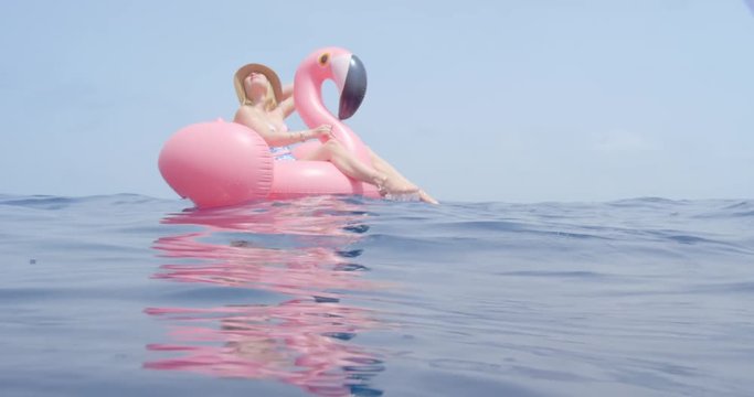 Woman lying on inflatable flamingo floating in middle of ocean girl relaxing in summer sunshine enjoying tropical vacation