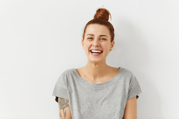 Happy cheerful young woman wearing her red hair in bun rejoicing at positive news or birthday gift,...