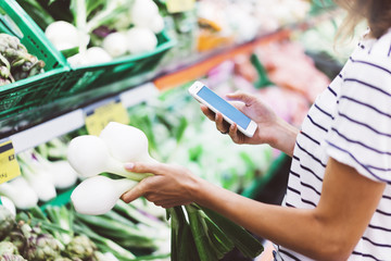 Young woman shopping healthy food in supermarket blur background. Female hands buy onion products...