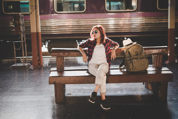 Young hipster woman waiting on the station platform with backpack. Travel concept.