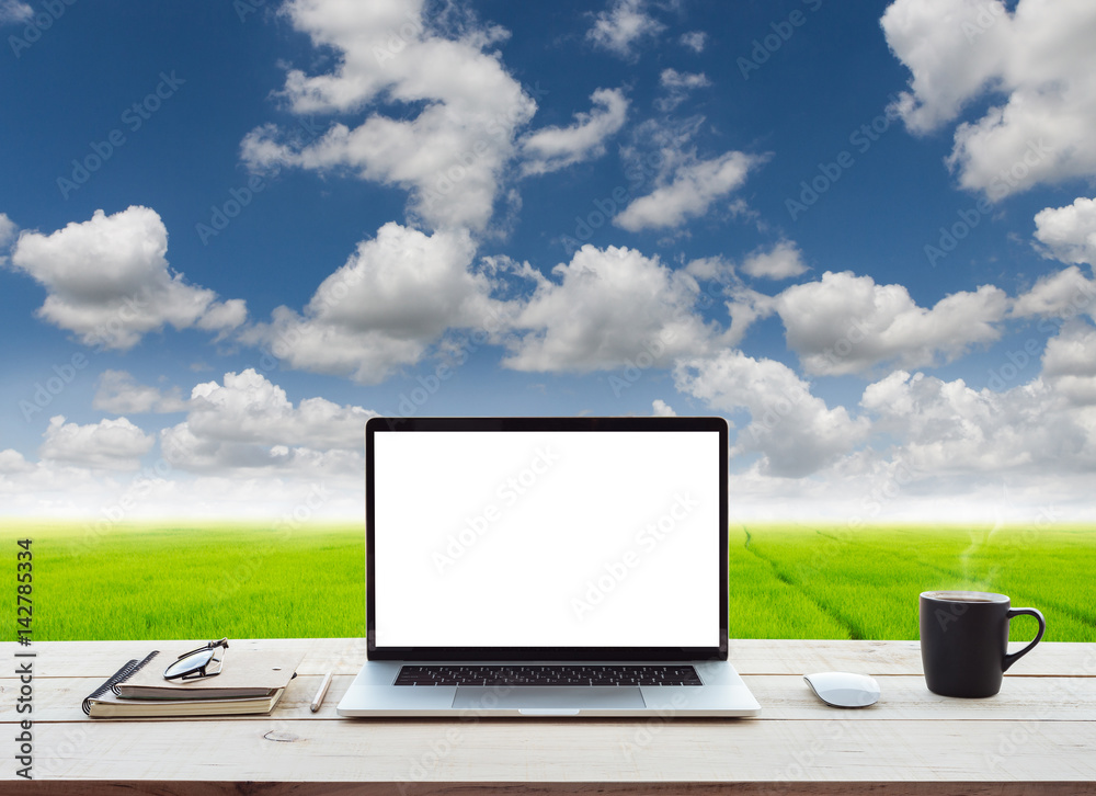 Aufkleber laptop computer showing white screen on work table meadow and blue sky view background