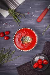 Tomato cream soup with thyme and black sesame seeds on a dark background