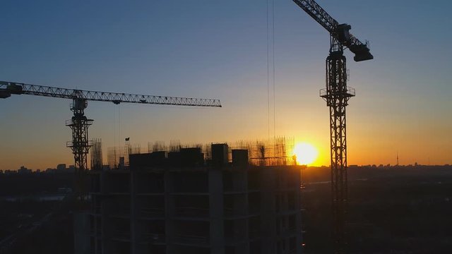 Aerial shot of construction site with cranes and workers at sunset