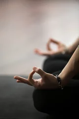 Foto op Canvas Mudra-gebaar uitgevoerd met vrouwelijke vingers, vrouw mediterend in lotushouding, zittend in Padmasana-oefening, studio- of thuisachtergrond, verticale foto. Meditatie sessie concept. Ruimte kopiëren. Detailopname © fizkes