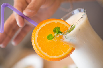 in the hands of a milkshake with a slice of lemon and a straw