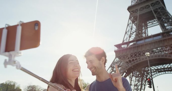 Tourist couple taking selfie photograph under Eiffel Tower Paris smartphone in city sharing lifestyle photo enjoying  holiday European   vacation travel adventure 