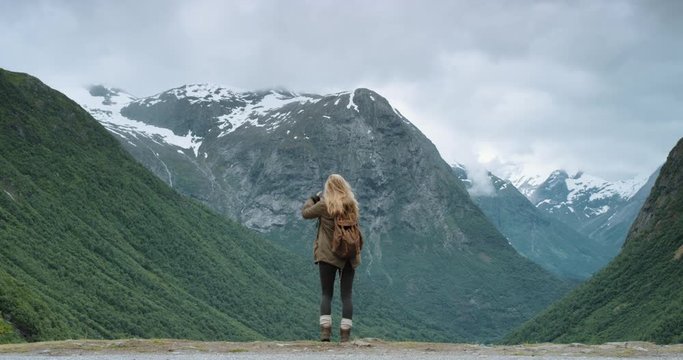 Woman taking photograph snow capped mountains smartphone photographing scenic landscape nature background view enjoying vacation travel adventure Norway