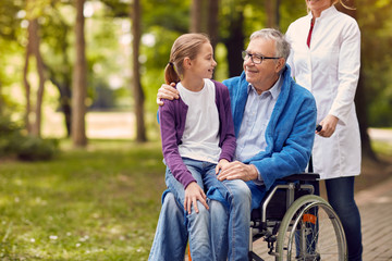 Obraz na płótnie Canvas Senior man on wheelchair with his granddaughter.
