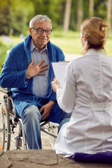 Fototapeta na wymiar elderly man in wheelchair who don't feel good with nurse.