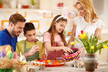 Family painting colorful eggs and preparing for Easter