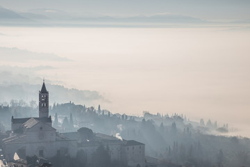 Beautiful view of the St. Clare church in Assisi (Italy) with fog below and in the background - obrazy, fototapety, plakaty