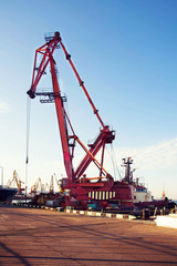 Fototapeta na wymiar Port cargo crane over blue sky background. Sea port, crane for loading at sunset. Transportation