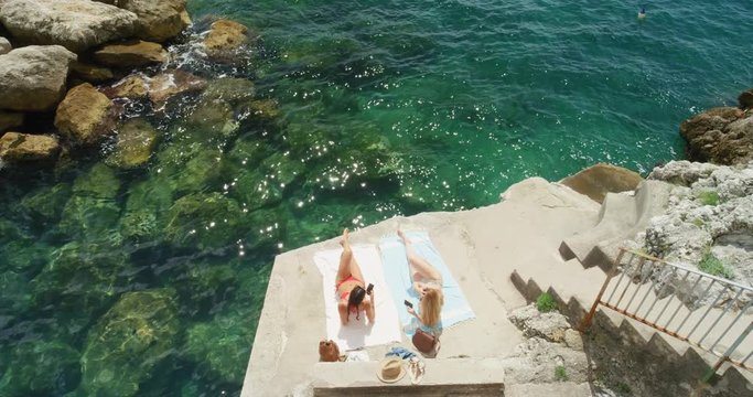 Top View of two young woman tanning in mediterranean bay with steps down to beach enjoying summer holiday  Amalfi Coast Italy on european travel adventure from above
