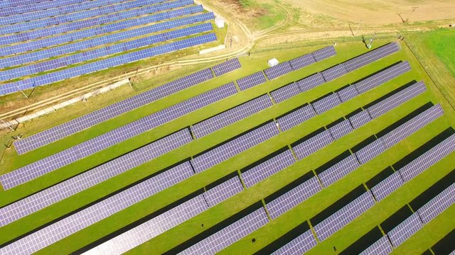 Camera flight over a solar power plant in agricultural landscape. Industrial background on renewable resources theme. Industry of power and fuel generation in European Union. 