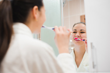 Portrait of young beautiful woman brushing her teeth with toothbrush