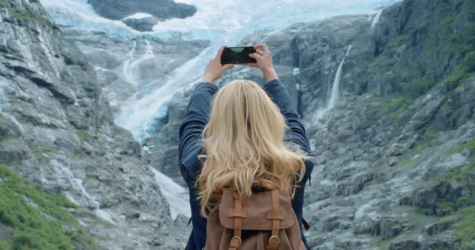 Brave explorer Woman taking photograph of melting glacier with smartphone photographing Climate change concept scenic landscape nature background view enjoying vacation travel trekking adventure close up