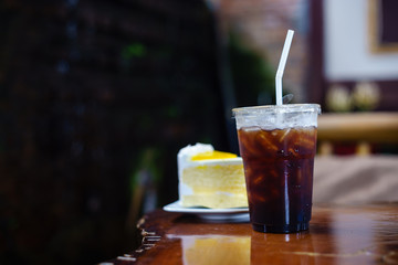 ice americano with orange cake on wood table.