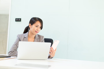 Businesswoman woman using cellphone and laptop computer in conference room