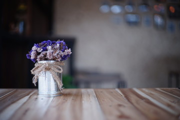 purple flower in aluminium pot on wood table at cafe.