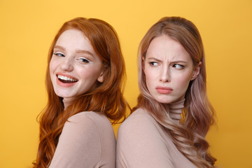 HAppy young redhead lady near angry blonde woman.