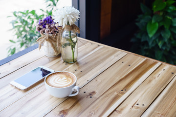 latte art coffee with smartphone or tablet on wood table.
