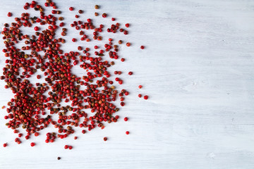 PInk peppercorns - famous brasilian spice - on white wooden table. Copy space.