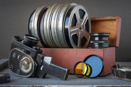 Reels with films in a wooden box, lens and an old movie camera