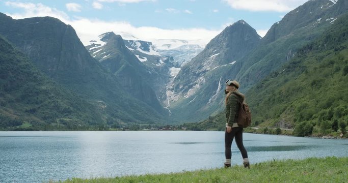 Brave woman hiker traveler looking at Glacier Norway wearing virtual reality headset enjoying outdoor travel experience  watching 360 video climate change imagination concept
