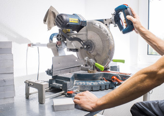 mechanic sawing metal part of the machine
