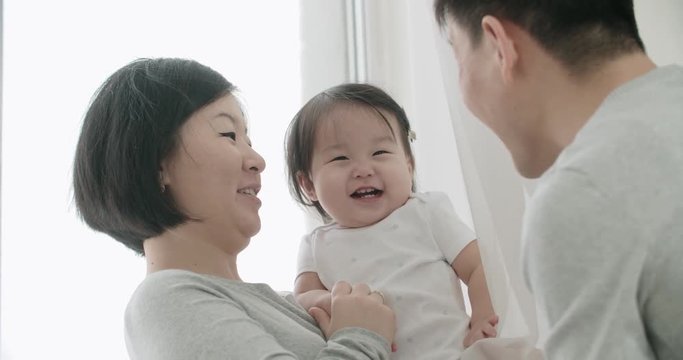 slow motion, young happy Asian couple with a baby in the bedroom,happy moments in the family