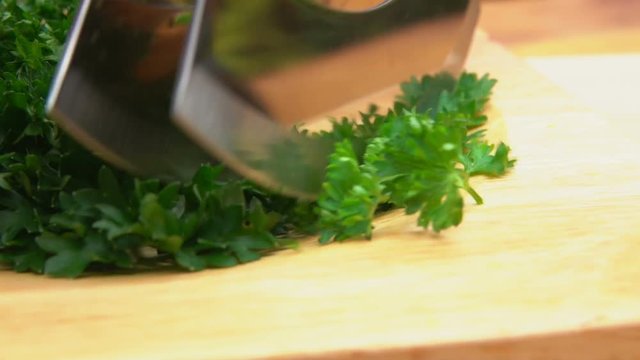 sliced green curly parsley on a wooden board with a special knife