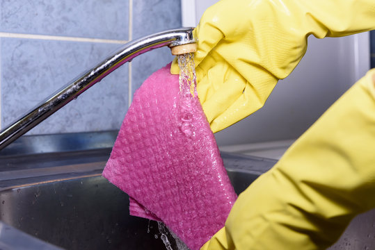 Scrubbing tiles in the kitchen with yellow gloves