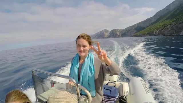Cool Girl driving speed boat through ocean on wild travel adventure freedom peace sign vacation 