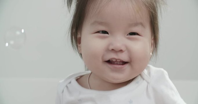 little Asian girl 1 year,having fun on the bed in the room , emotionally expresses joy