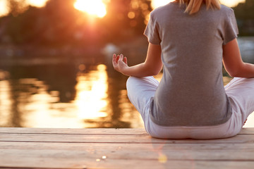 Meditation in yoga position near river - back view