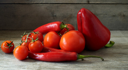 still life of red vegetables - tomatoes, bell pepper, chili and cherry tomatoes on wooden table, suitable for header or banner