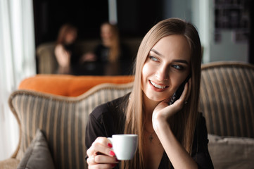 a woman with cute smile having mobile phone conversation while resting after work day in cafe