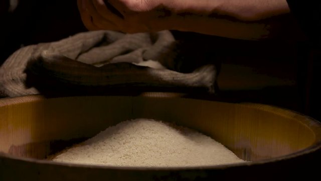 Hands with rice in slow-mo. Groats falling on pile.