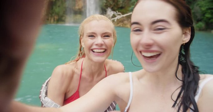 Attractive girl friends taking selfie photograph with smartphone woman enjoying swimming in waterfall nature background view enjoying vacation travel adventure POV