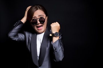 Woman wearing sun glassesin black suit check her watch she is late