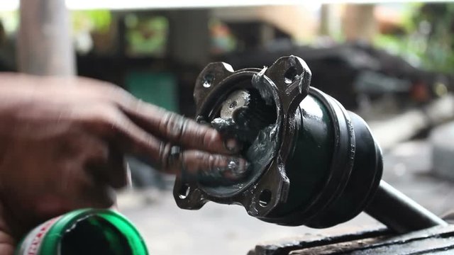 mechanic doing maintenance applying grease to shaft