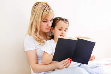 happy family mother child daughter little girl reading a book by the window