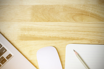 Notepad and laptop on wood table. View from above