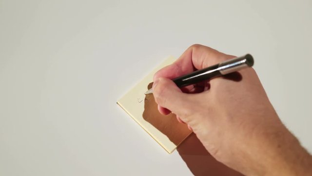 Person writing on stick note reminder telephone number