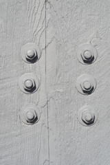 six bolts on gray painted wood beam close up