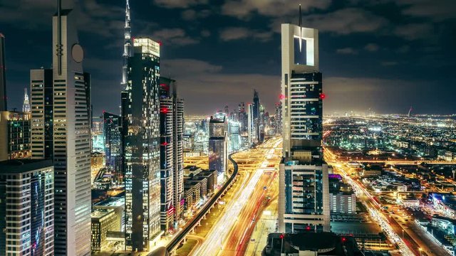 Downtown Dubai skyscrapers at night. Scenic aerial view of famous highway with fast moving traffic. 4K time lapse.