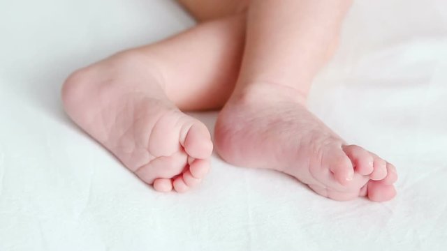 feet of a newborn lying on white bed at home